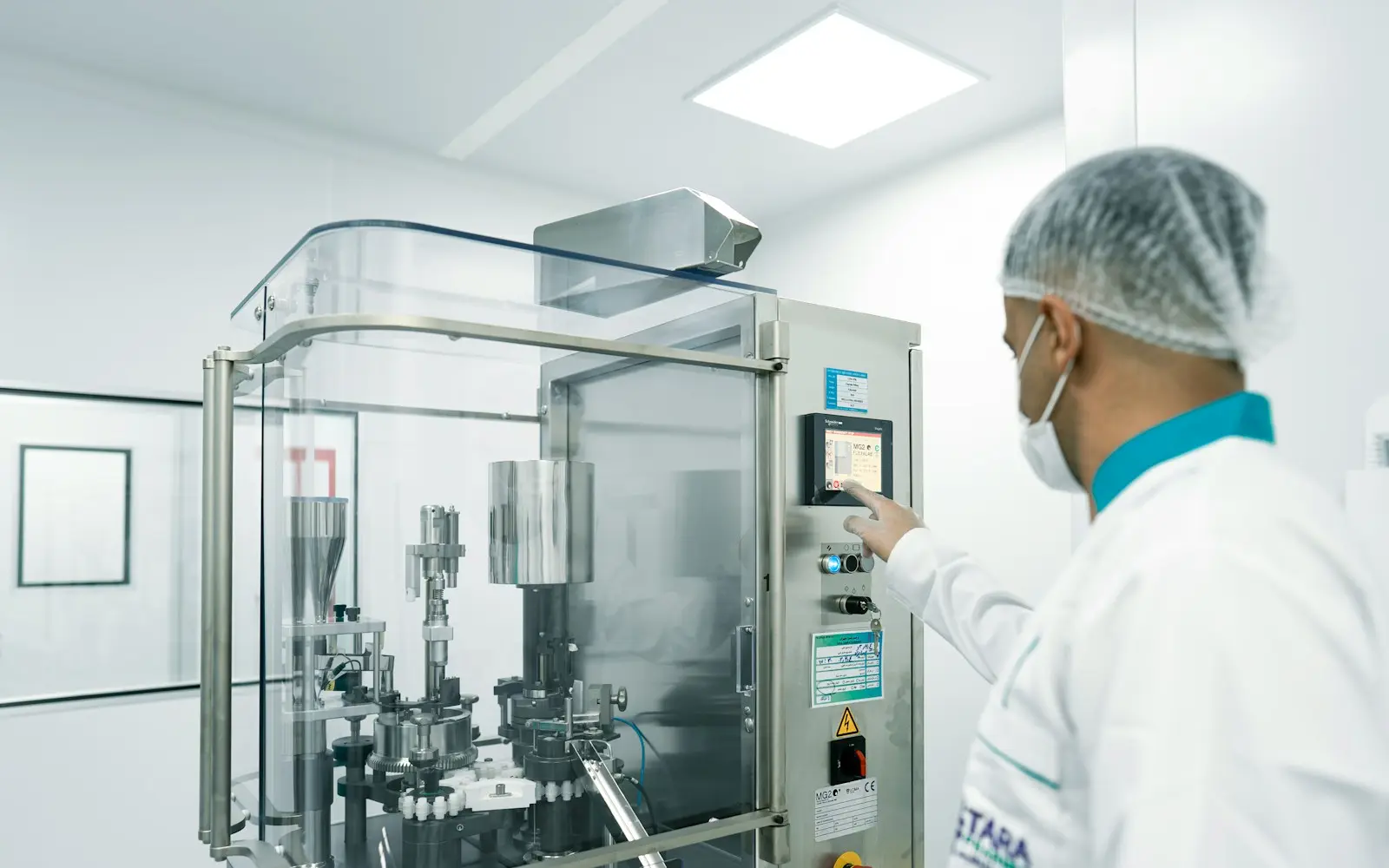 A technician operating a capsule machine in a cleanroom